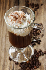 Irish coffee on wooden table among coffee beans