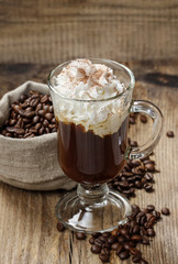 Irish coffee on wooden table among coffee beans