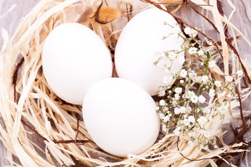 weisse eier mit blüten im nest aus stroh ostern dekoration