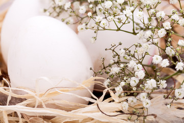 weisse eier mit blüten im nest aus stroh ostern dekoration