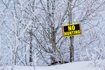 No hunting sign posted in front of frost covered trees