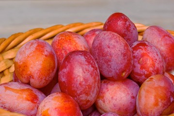 Closeup of fresh plums in weaved basket.
