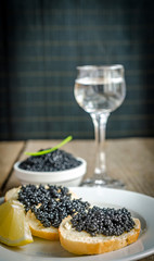 Sandwiches with black caviar and glass of vodka
