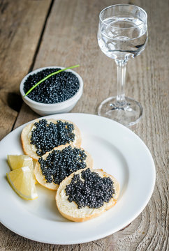 Sandwiches with black caviar and glass of vodka
