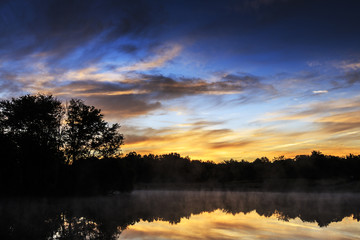 Beautiful sunrise with tree reflections in a lake