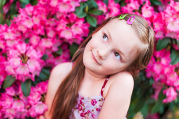 Fototapeta premium Cute little girl is daydreaming in pink flowers