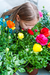Obraz na płótnie Canvas Little girl smelling flowers in flower shop