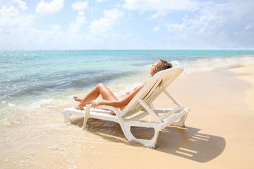 Woman relaxing in long chair by the beach