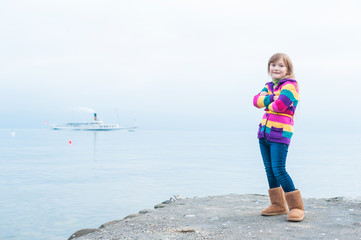 Outdoor portrait of a beautiful little girl in colorful jacket