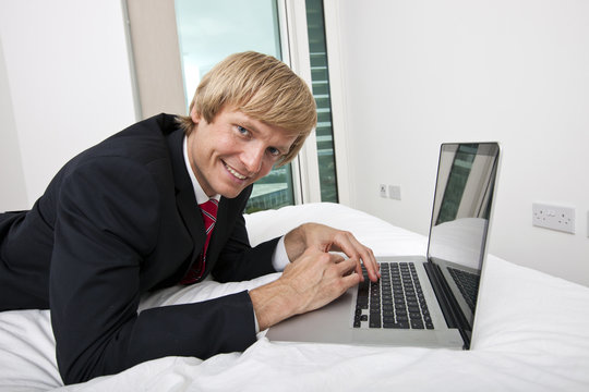 Portrait of mid adult businessman using laptop in bed at home