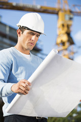 Male architect examining blueprint at construction site