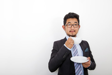 Portrait of confident young businessman holding coffee cup and plate over white background