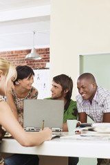Four people having meeting around laptop.