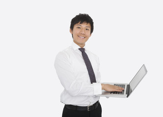 Portrait of happy mid adult businessman using laptop over white background