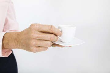 Cropped image of senior businesswoman with espresso cup at office