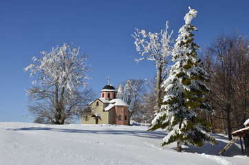 Church between trees on the snow landscape