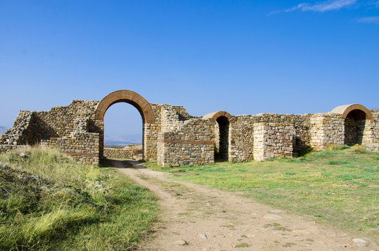 ancient town ruins and path through arced stone gate