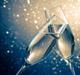 champagne flutes with bubbles on blue light bokeh background