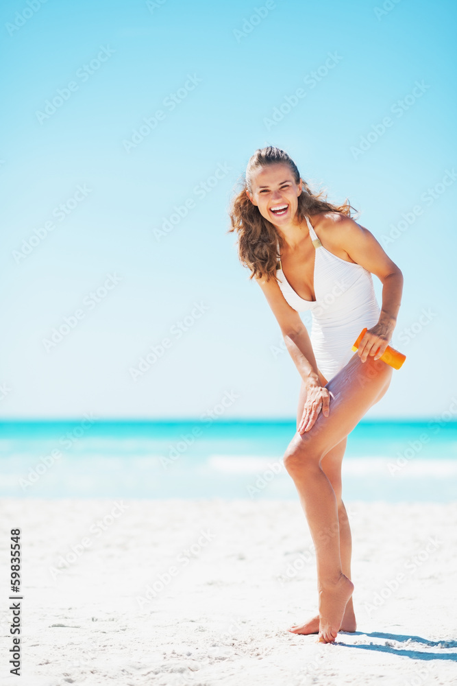 Poster full length portrait of smiling woman applying sun screen creme