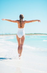 Fototapeta na wymiar Full length portrait of young woman rejoicing on beach