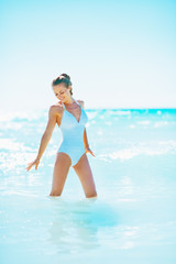 Full length portrait of happy young woman standing in sea