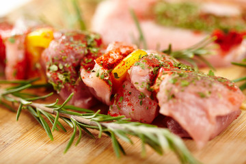 Spit of spiced raw pork meat with pepper on a wooden board