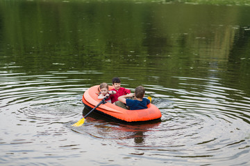 children floating in a rubber boat on the pond