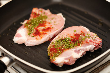 Spiced raw pork chops in the frying pan