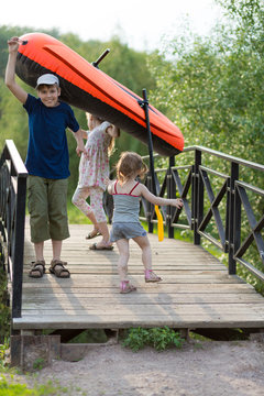 Three children with a boat on a wooden bridge
