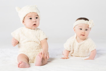 Two baby dressed in white fur in studio