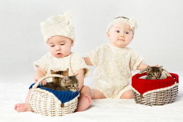 Two babies in white fur with two basket with small kittens