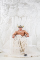 A muscular man in viking helmet  with snow on body