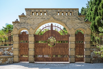 Beautiful wrought-iron gates in brick arch on nature