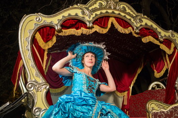 Obraz premium girl in old-fashioned dress correct the hat in carriage