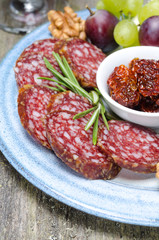 snacks on a plate - sausage, sun-dried tomatoes, nuts, fruits
