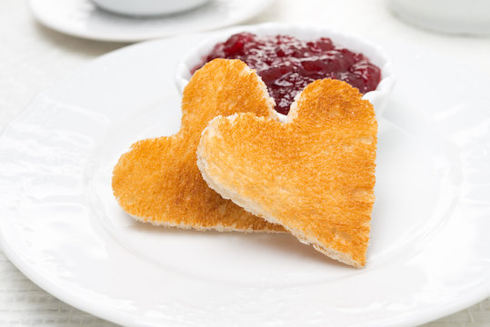 Two toast bread in the shape of heart and berry jam on the plate