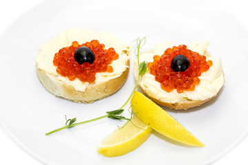 canape with red caviar and lemon on white background