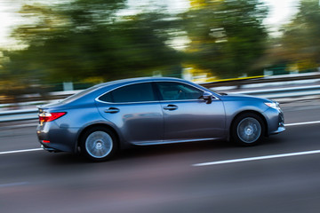 Plakat Nowoczesny samochód sportowy przyspieszenia wzdłuż drogi z motion blur