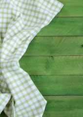Wooden background with green checkered kitchen towel
