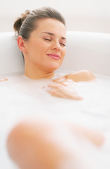 Obraz na płótnie Canvas Happy young woman relaxing in bathtub