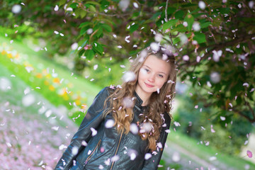 Girl under falling flower petals on a spring day