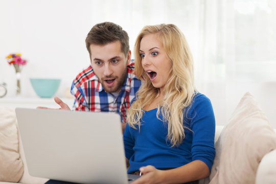 Shocked couple looking at contemporary laptop