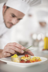 closeup on chef's hands garnishing a plate