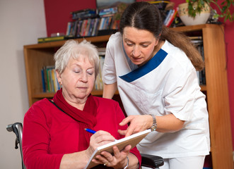 nurse is helping a old woman with a form