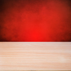 Empty wooden table over over red grunge background