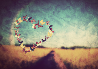 Heart shape made of butterflies on vintage field background