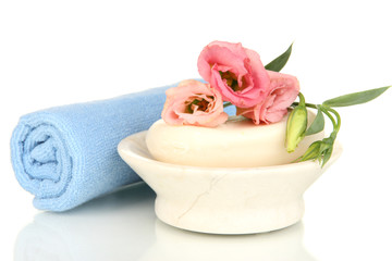 Rolled blue towel, soap bar and beautiful flower isolated