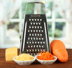 Metal grater and carrot, cheese, on bright background