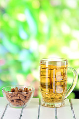 Beer in glass and croutons  on table on nature background