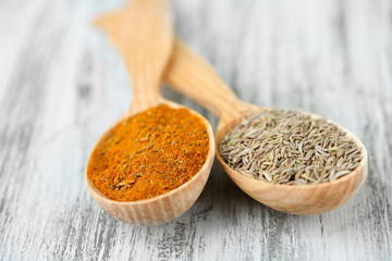 Assortment of spices in wooden spoons on wooden background